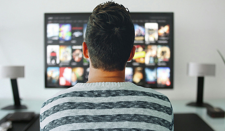 A Man streaming videos on television through a cutting-edge OTT platform.