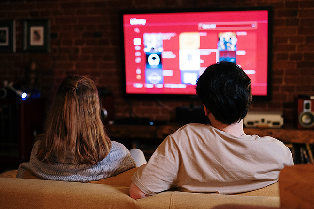 Couple streaming on-demand videos on TV via OTT platform.