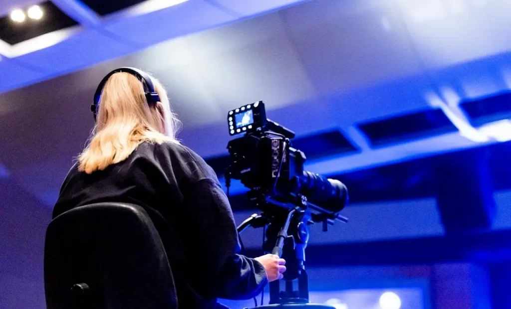 Broadcast technician is managing a live production, smoothly using cloud technology to send feeds, showcasing the blend of expertise and modern cloud solutions in broadcasting.